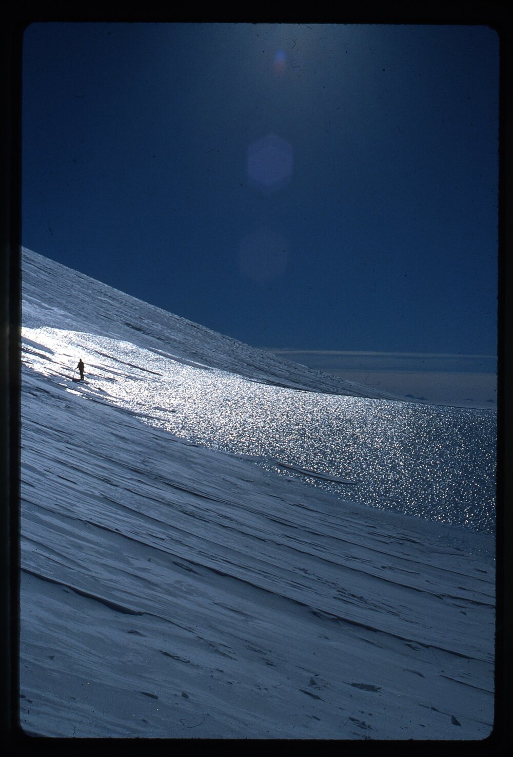 Person silhouetted on wind-scoured ice, north side of Alligator Peak, Shelton Glacier