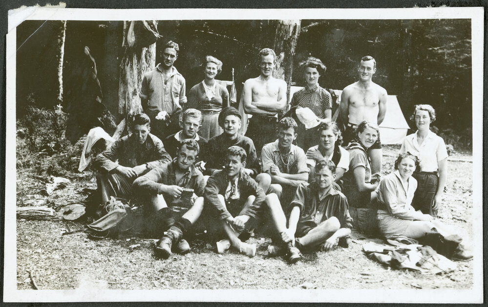 [Group image of the tramping party, standing in front of their campsite.]