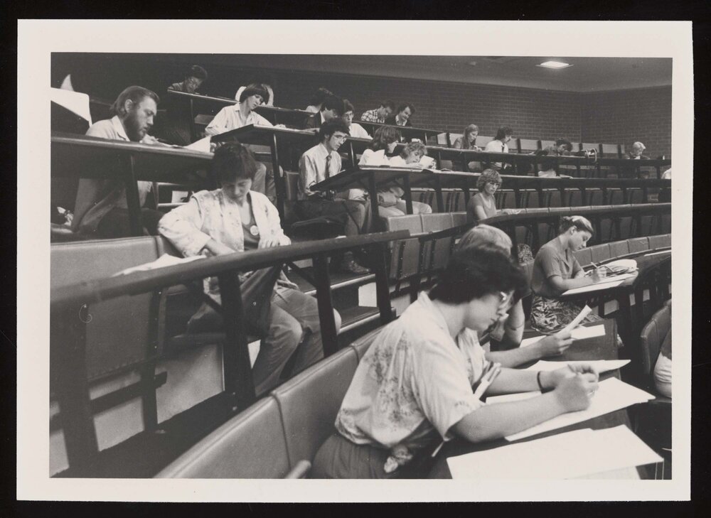 Students filling out forms in a lecture theatre (c)