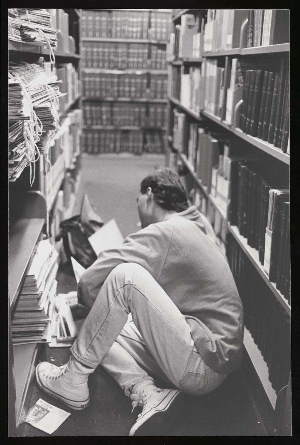Student reading on the floor between library shelfs