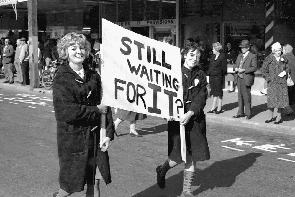 Students with sign 'Still waiting for it?' at the annual student procession