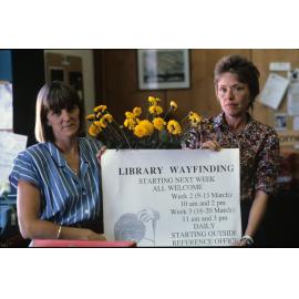 Slide 27 Margaret Ferguson (Reference 1st Assistant), Barbro Harris (Head of Reference) holding library wayfinding sign