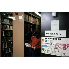 Slide 47 Student reading book between shelves