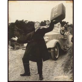 Man in suit with suitcase reading "Tokyo" being chased by men in car
