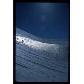 Person silhouetted on wind-scoured ice, north side of Alligator Peak, Shelton Glacier