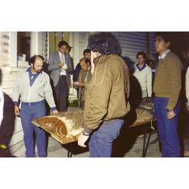 People waiting outside with the carved poupou Taraika on a table