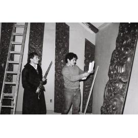 Pou Temara(?) and Tākirirangi Smith consulting plans durng installation of poupou inside wharenui