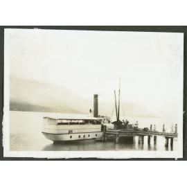 [Image of a steamboat on a lake with people on the docks.] 