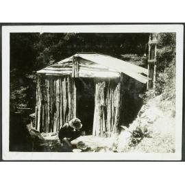 Tawhai Hut. [Image of a man crouching outside a wooden hut.]