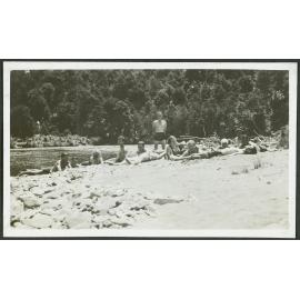 Sunbathing. [Image of a group of people in swimming gear, lying on a river bank in the sun.]