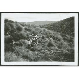 [Image of a group of people sitting among tussock grass.]