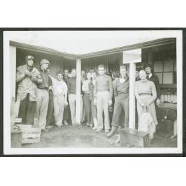 [Group photo of tramping party under a verandah.]