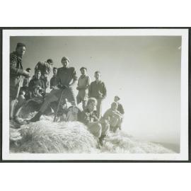 [Group image of men standing in tussock grass.]