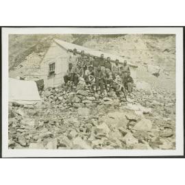 [Image of a tramping group sitting on rocks outside a hut.]