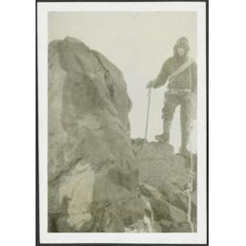 [Image of a man in climbing gear standing on top of a rock.]