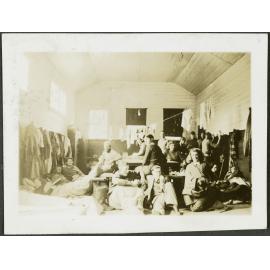 The Schoolhouse. [Image of a group of trampers inside a hut.]