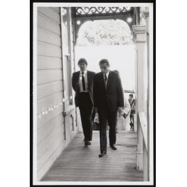Two men walking along marae porch
