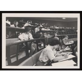 Students filling out forms in a lecture theatre (c)