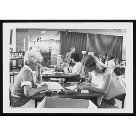 Mrs June Scannell sitting at a desk with a student who is filling out forms during enrolment