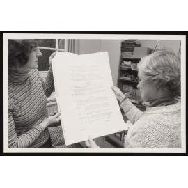 Examinations Officer  and assistant holding  an extra large exam paper 