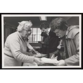 Admin staff handing out exam papers to students