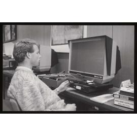 Student using a microfiche reader in the library