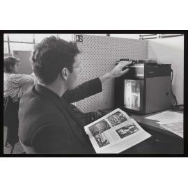 Student using a slide projector in the library