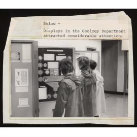 Three people looking at a display in the Geology Department