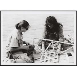 Two students building a raft[?] structure