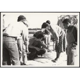 Student group looking at architectural plans on a work site