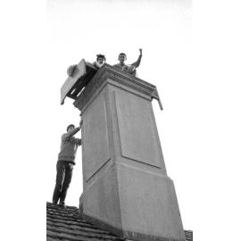Students on the roof of Weir House, posing atop a chimney