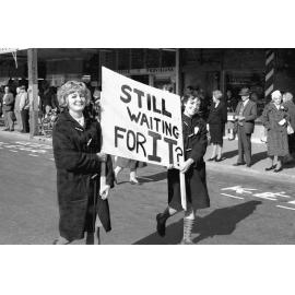 Students with sign 'Still waiting for it?' at the annual student procession