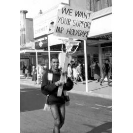 Student holding a sign addressing Mr Holyoake at the annual student procession